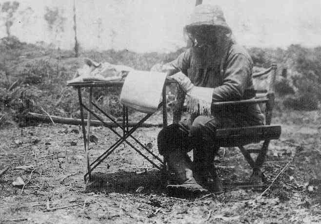 Roosevelt at his portable writing desk, wearing mosquito netting